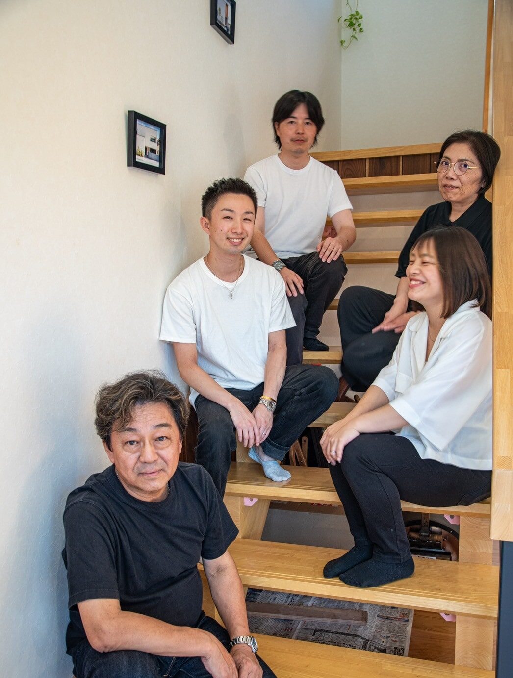 事務所の階段に腰かけて笑顔で並ぶスタッフ5名
