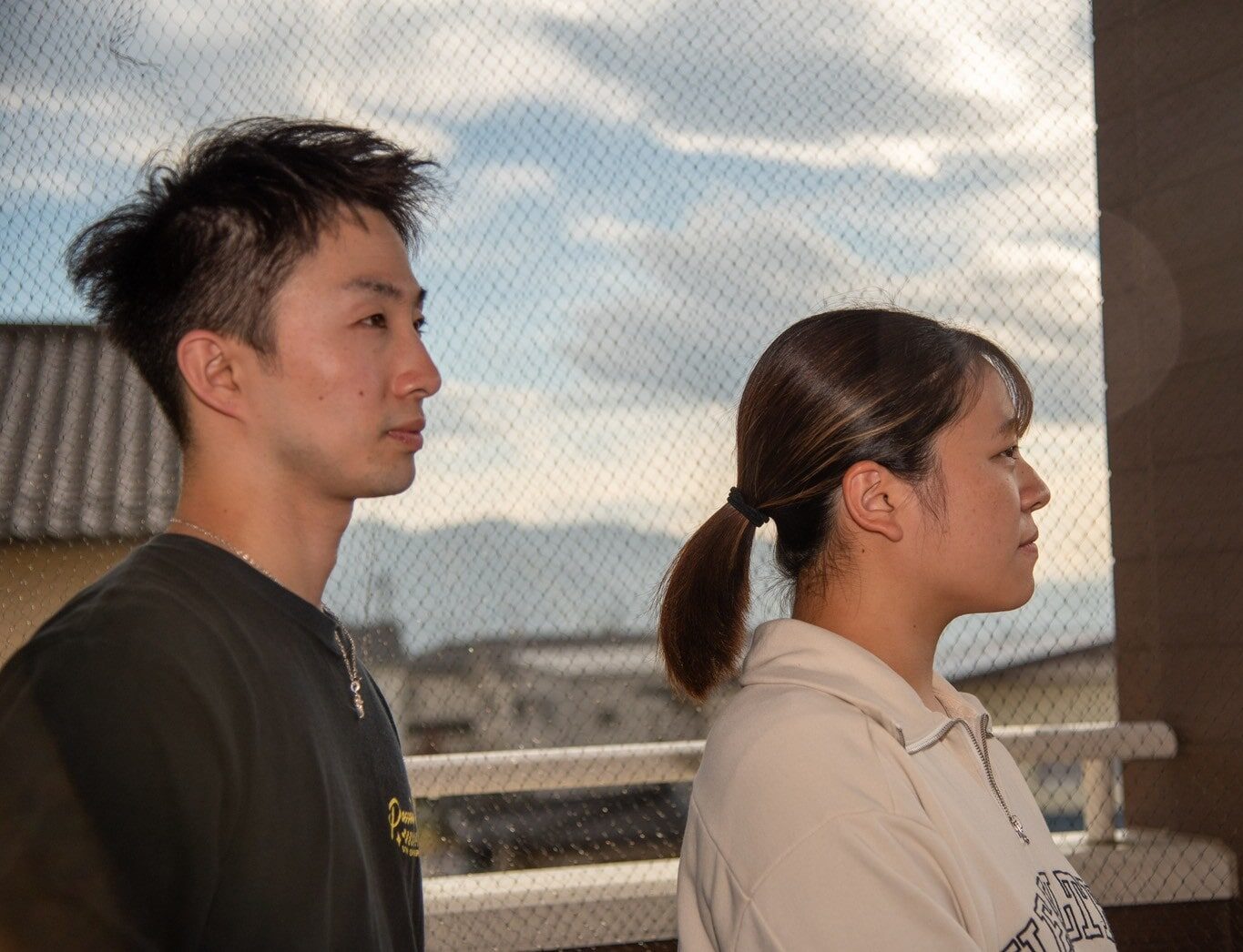山並みの見えるバルコニーで、遠くを見つめる男女2名のスタッフ